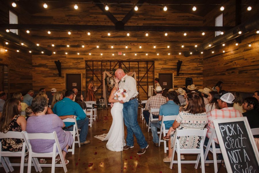 newlyweds share a kiss in aisle as family and friends celebrate the happy couple 