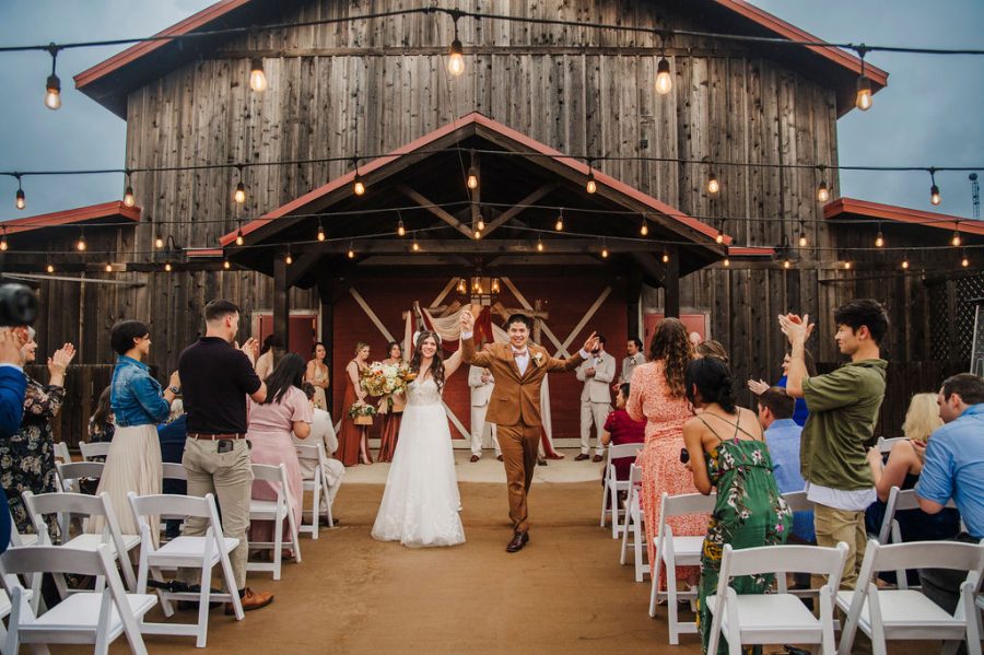 just married couple walks up the aisle of their barn patio ceremony as family and friends celebrate