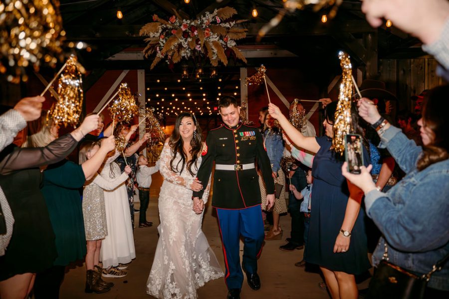 newlyweds walk through a sparkler sendoff through open barn doors with stringlights in background